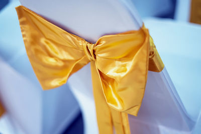 Golden yellow cloth decorated the white chair with bow.