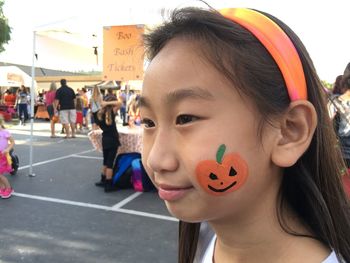 Close-up of girl with painted pumpkin on cheek during event