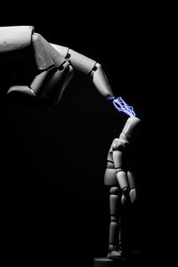 Close-up of hand holding umbrella over black background