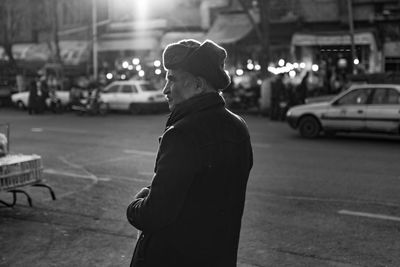 Side view of man standing on street in city at night