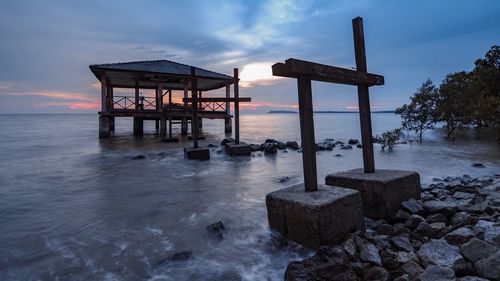 Lifeguard hut on beach against sky during sunset