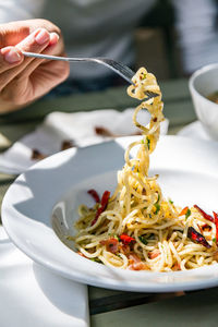 Cropped hand having pasta at table