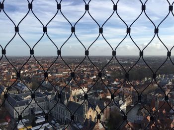 Close-up of cityscape seen through chainlink fence