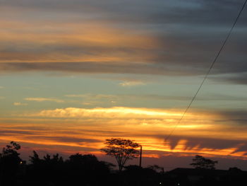 Low angle view of silhouette trees against dramatic sky