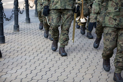 Soldiers on parade march with brass instruments.