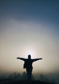 Rear view of silhouette person standing against sky during sunset