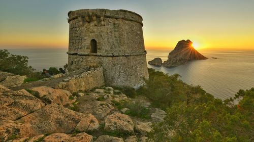 Old ruins by sea during sunset