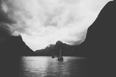 Boats in sea against cloudy sky