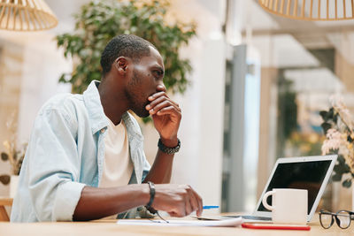 Side view of young man using mobile phone in office