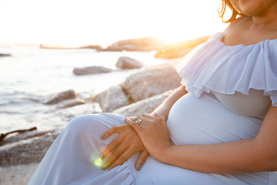 Midsection of woman sitting on beach