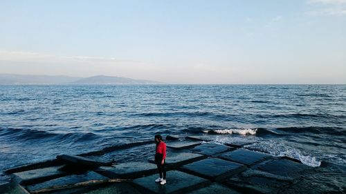 Woman standing on sea shore against sky