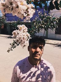 Portrait of young man against white flowering plants