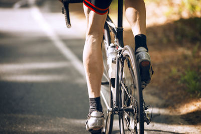 Low section of cyclist riding bicycle on road