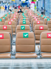 Rows empty brown chairs with the sticker sign sitting position for social distancing in  airport 