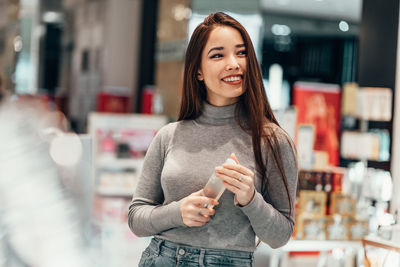 Portrait of a smiling young woman standing in store