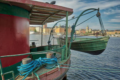 Fishing boats moored at harbor against sky