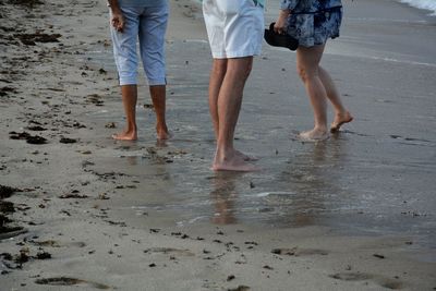 Low section of friends standing at beach