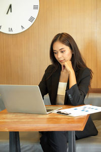 Young woman using mobile phone while sitting on table