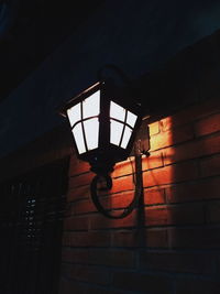 Low angle view of illuminated lamp hanging on wall