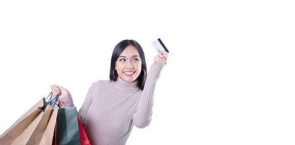 Portrait of smiling young woman using phone against white background