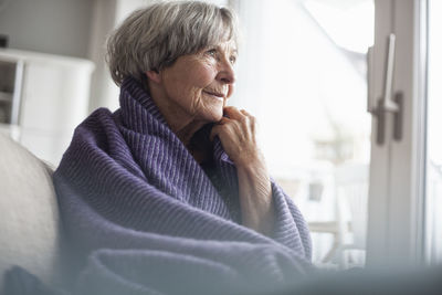 Portrait of pensive senior woman sitting on couch at home