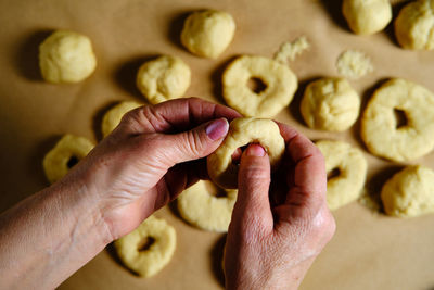 Top view of anonymous woman making rings from soft dough while preparing doughnuts over table in kitchen