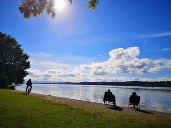 People by lake against sky