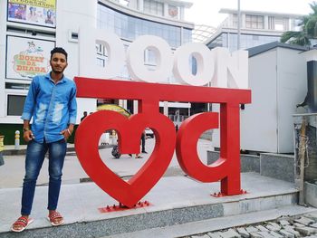 Full length portrait of smiling man standing by building