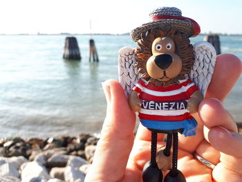 Midsection of woman holding hands at beach against sky