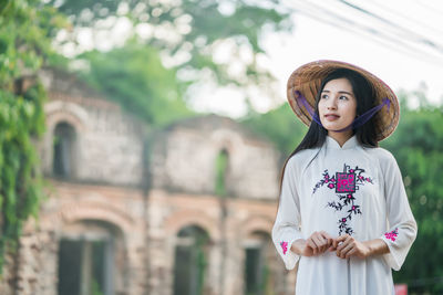 Smiling young woman standing against building