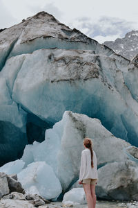 Rear view of woman standing on mountain during winter