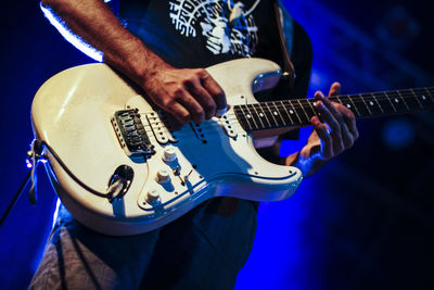 Midsection of man playing guitar in concert