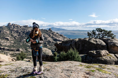 Man standing on rocks looking at mountain against sky