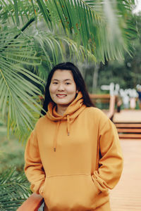 Portrait of young woman standing against plants