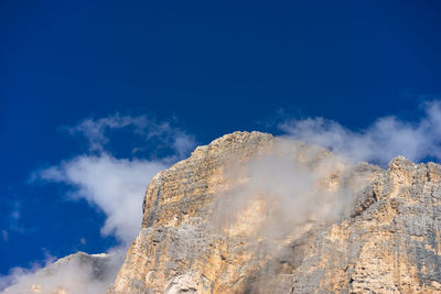 Low angle view of tofana di rozes against blue sky