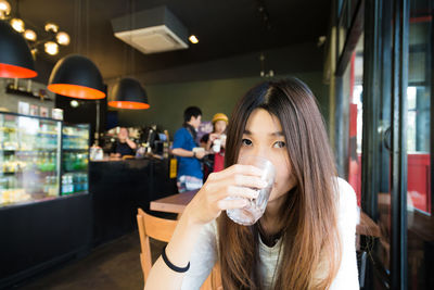 Portrait of woman drinking glass in restaurant