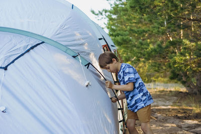 Cute little caucasian boy helping to put up a tent. family camping concept