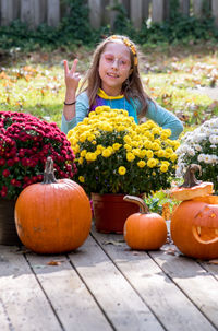 A little girl dressed as a hippie flower child for halloween,  flashes a peace sign 