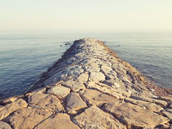 Scenic view of rocks on sea against clear sky