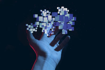 Cropped hand holding jigsaw pieces against black background