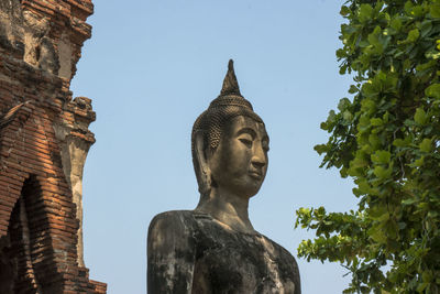 Low angle view of buddha statue against sky