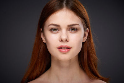 Close-up of young woman against black background