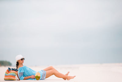 Rear view of man sitting on beach against sky