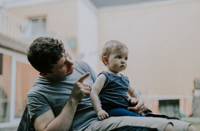 Portrait of caucasian dad pointing with finger talking to a little girl in her arms