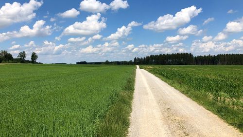 Road amidst field against sky