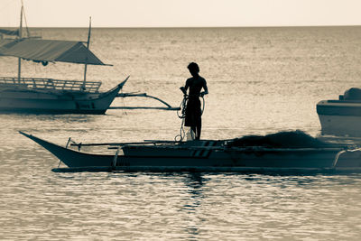 Rear view of man standing on sea against sky