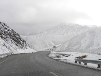 Scenic view of a road and snowcapped mountains against sky
