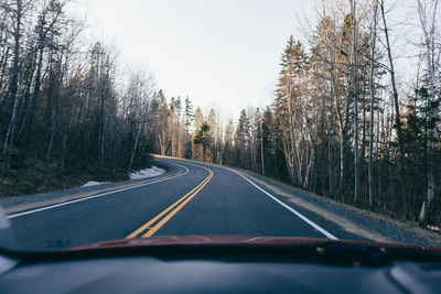 Road amidst trees seen through car windshield