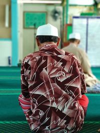 Rear view of man sitting in mosque