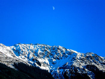 Scenic view of snow covered mountains against blue sky